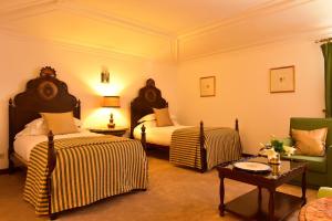 une chambre d'hôtel avec deux lits et un canapé dans l'établissement Pousada Castelo de Estremoz, à Estremoz