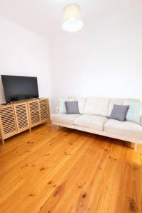 a living room with a white couch and a flat screen tv at 2BR Beachfront Escape in Largs North in Semaphore
