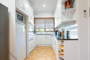 a kitchen with white cabinets and a white refrigerator at 2BR Beachfront Escape in Largs North in Semaphore