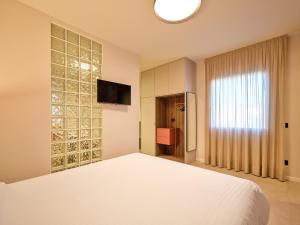 a bedroom with a white bed and a television at Residence Al Centro in Pescantina