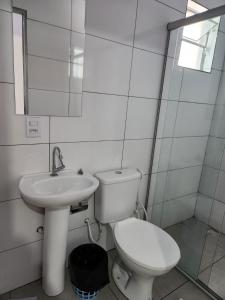 a white bathroom with a toilet and a sink at Apart hotel in Três Marias +3 photos