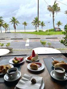 a table with plates of food on it with a view of the beach at Suíte aconchegante beira mar - Suíte 255 in Guarujá