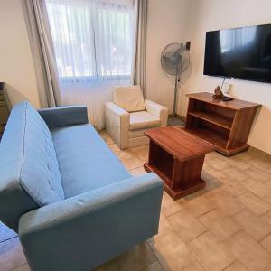 a living room with a blue couch and a tv at Casa VLG 5 pax in Las Grutas