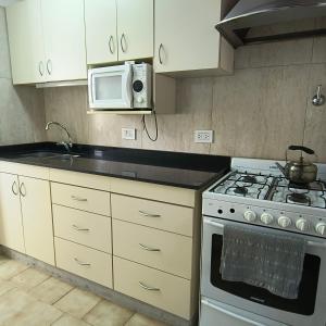 a kitchen with a stove and a microwave at Casa VLG 5 pax in Las Grutas