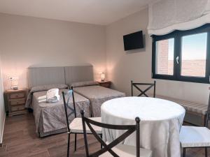 a bedroom with two beds and a table and chairs at Alojamiento rural Solterra in Roa