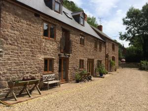 a stone building with benches in front of it at Woodmill Farm Apartment in Alvington