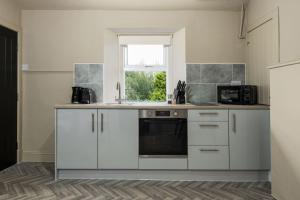 a kitchen with white cabinets and a sink and a window at The Wallace Suite by The Wallace Monument in Stirling