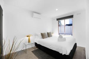 a white bedroom with a bed and a window at Sunshine Family Sophistication in Albion
