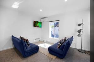 a living room with two blue chairs and a glass table at Sunshine Family Sophistication in Albion