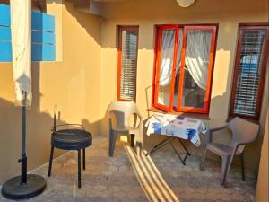 a patio with chairs and a table and a window at Vitamiene-See Hartenbos in Hartenbos +3 photos