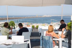 a group of people sitting at tables near the beach at House Barra Beach in Praia da Barra +62 photos