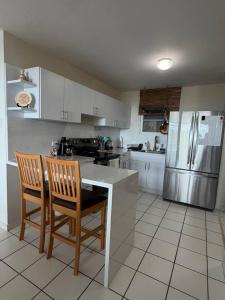 a kitchen with a counter and two chairs and a refrigerator at Tropical Escape in Ceiba