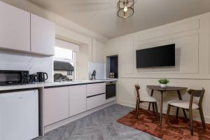 a kitchen with white cabinets and a table with chairs at Caledonia Suite by The Wallace Monument in Stirling