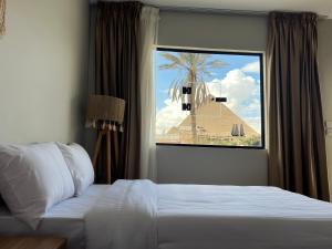 a bedroom with a bed and a palm tree outside a window at Calm Pyramids View Villa in Cairo