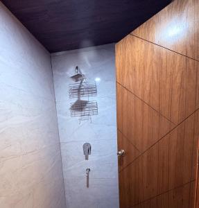 a bathroom with a shower with a wooden door at B&A Stays in Dehradun
