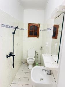 a white bathroom with a toilet and a sink at Bulle d'Or Serenity in Libreville