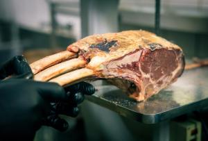 a person holding a piece of meat on a table at Afrique Boutique Hotel O.R. Tambo in Boksburg