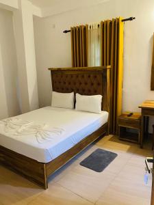 a bedroom with a large bed with a wooden headboard at New Arverne Villa Kandy in Kandy
