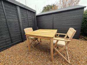 a wooden table and two chairs next to a fence at Rosewell Lower Dicker in Horsebridge
