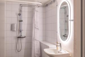 a bathroom with a sink and a shower with a mirror at Hotell Navet in Västervik