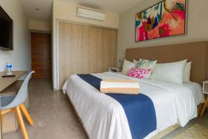 a hotel room with a large bed and a desk at Steps from 5th Ave with Rooftop Pool Gym & Cinema in Playa del Carmen