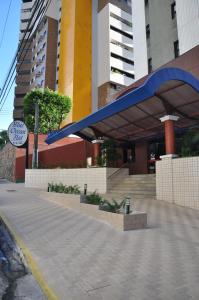 JOH Blue Ocean Flat Hotel في فورتاليزا: مبنى أمامه مظلة زرقاء