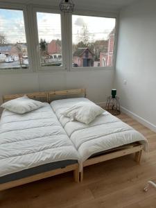 a bed in a room with two windows at Maison Solesmes nord in Solesmes