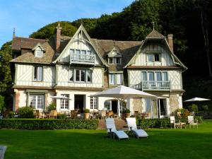 ein großes Haus mit Stühlen und einem Sonnenschirm im Hof in der Unterkunft Le Manoir des Impressionnistes - Bord de Mer in Honfleur
