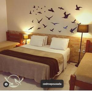 a bedroom with a bed with birds on the wall at Cedros Pousada in Guaramiranga