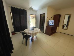 a living room with a table and chairs and a television at Cedros Pousada in Guaramiranga