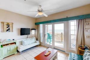 a living room with a couch and a tv at Oceanfront, dog-friendly condo with ocean view, pool & central AC in Hatteras