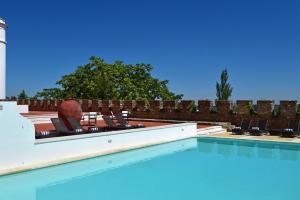 - une piscine avec des chaises à côté d'un mur en briques dans l'établissement Pousada Castelo de Estremoz, à Estremoz