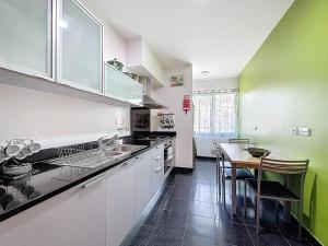 a kitchen with green and white walls and a table at Sea Garden in Caniço