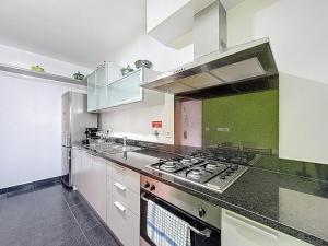 a kitchen with white cabinets and a stove top oven at Sea Garden in Caniço +9 photos