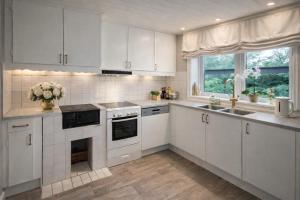 a white kitchen with white cabinets and a sink at Lilla Röda Huset. in Sjötofta