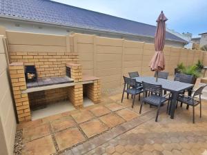a patio with a fireplace and a table and chairs at Vitamiene-See Hartenbos in Hartenbos