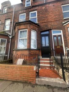 a brick house with a black door and stairs at Belles Haven in Belfast