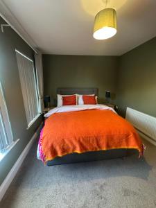 a bedroom with a bed with an orange blanket at Belles Haven in Belfast