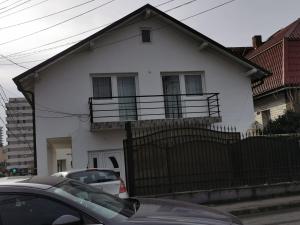 a white house with a balcony with cars parked in front at Danube House in Cluj-Napoca