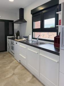 a kitchen with white cabinets and a sink at Casa Rural Solterra in Roa
