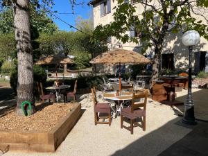 an outdoor patio with tables and chairs and umbrellas at Logis Hôtel LE DAHU in Parigny