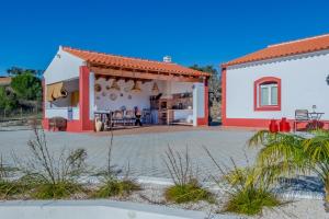 a white house with a red roof and a patio at Casa do Arlindo in São Bartolomeu de Messines