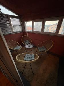 a room with three chairs and a table and windows at Apartman 23 in Belgrade
