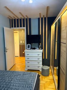 a bedroom with a bed and a dresser with a television at Apartman 23 in Belgrade