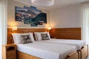 two beds in a hotel room with two lamps at Hotel Rododendro Val di Fassa in Campitello di Fassa