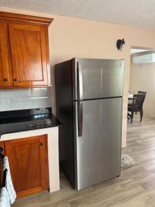 a kitchen with a stainless steel refrigerator and wooden cabinets at Rawacou Breeze in Kingstown +1 photo