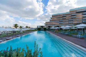 a swimming pool in front of a building with chairs and umbrellas at Th8 Palm Dubai Beach Resort, Vignette Collection by IHG in Dubai