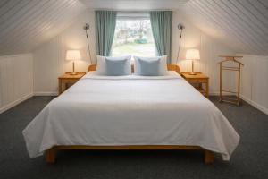 a bedroom with a large white bed with two lamps at Lilla Röda Huset. in Sjötofta