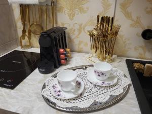 a counter with two cups and saucers on a table at Jázmin Apartman in Debrecen