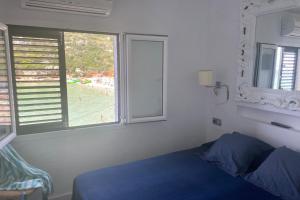 a bedroom with a blue bed and a window at Beachfront Apartment in Calan Porter Menorca in Cala en Porter
